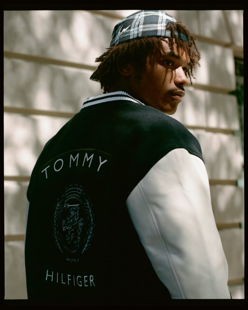 Nile Winchester looks over his shoulder in a Tommy Hilfiger varsity jacket and plaid cap.