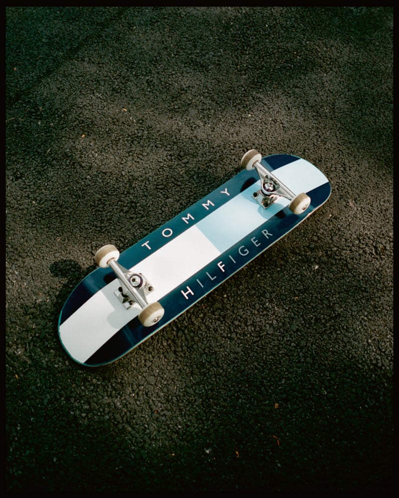 A Tommy Hilfiger x FRGMT skateboard rests on the pavement.