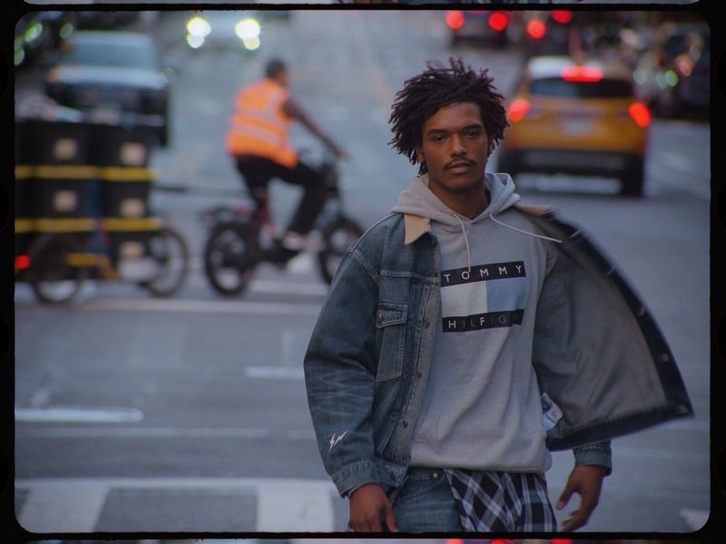 Nile Winchester wears a denim jacket over a gray logo hoodie on a New York street.