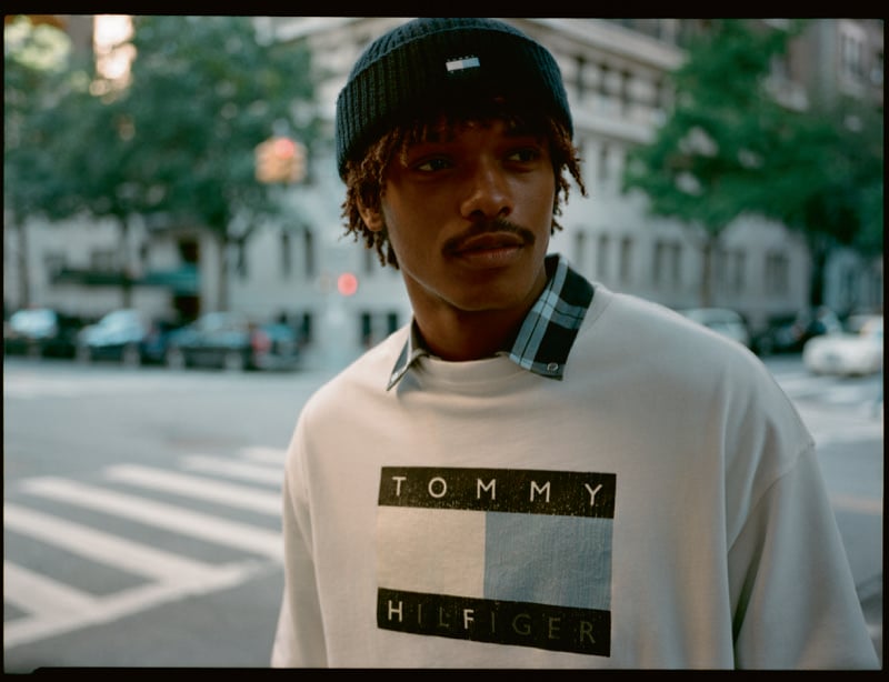 Nile Winchester wears a white logo T-shirt over a plaid shirt on a New York street.