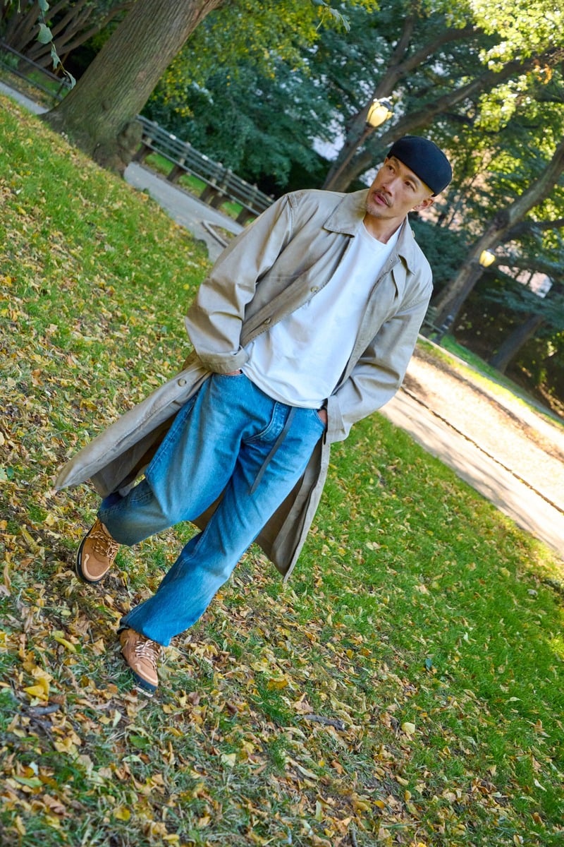 Dao-Yi Chow wears a long trench coat and loose blue jeans with chestnut UGG Lowmel Guard GTX shoes.