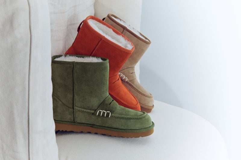 Khaki, Orange, and Chestnut UGG x JW Anderson loafer boots displayed on a white sofa.