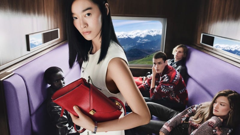 Ruiqi Jiang holds a red handbag aboard a train with Yar Aguer, Paolo Grebic in patterned red knitwear, Max Stenzel, and Reina Spoormaker.