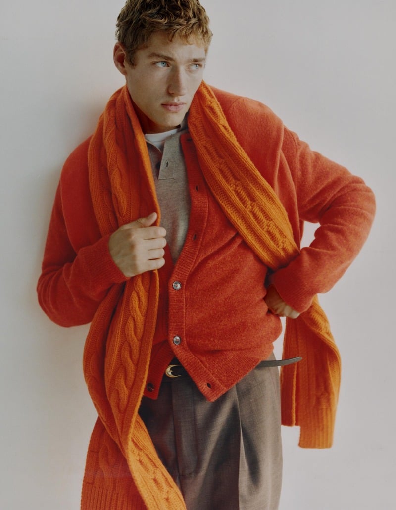 Valentin Humbroich wears an orange cardigan and scarf with gray trousers.