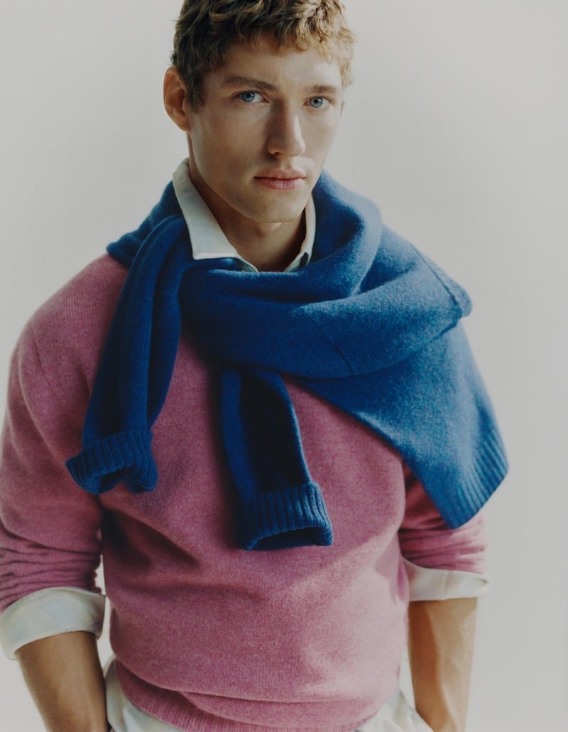 Valentin Humbroich wears a blue sweater around his shoulders over a pink knit and white shirt.