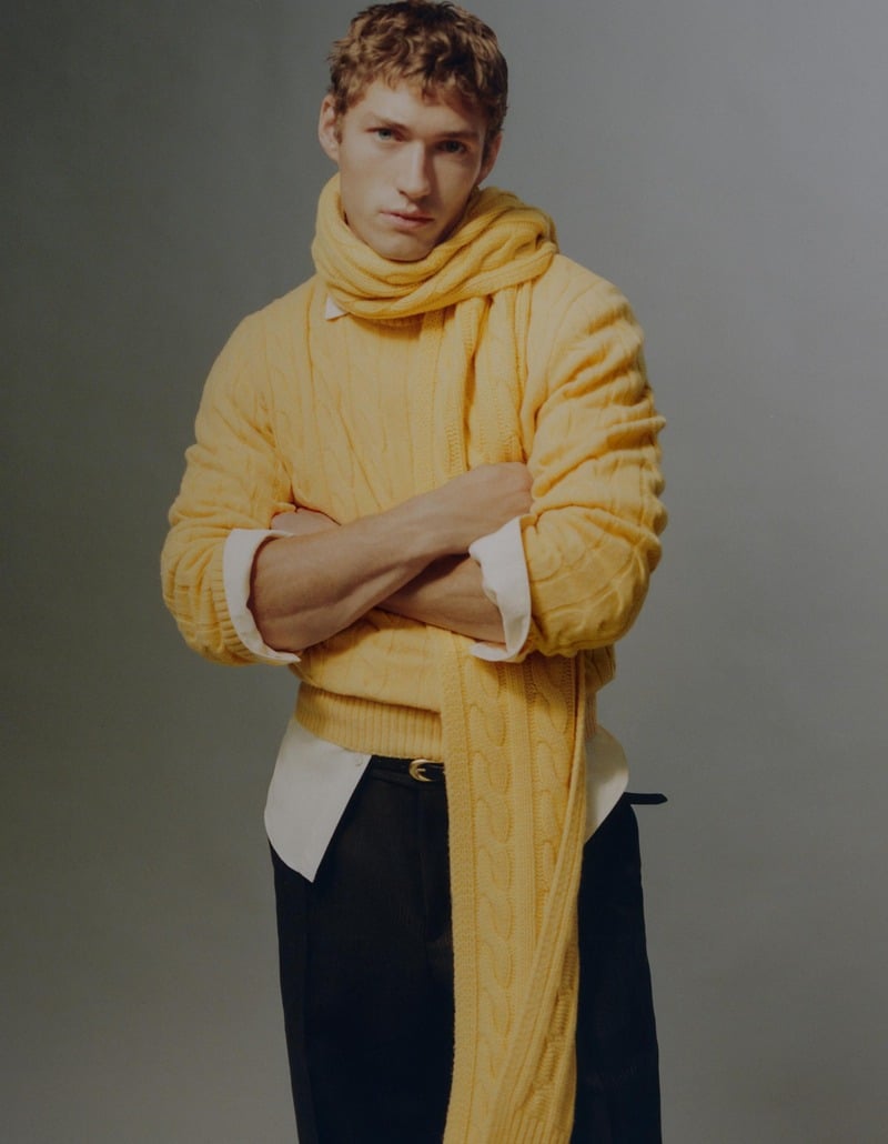 Valentin Humbroich folds his arms in a yellow cable-knit sweater and matching scarf over a white shirt.