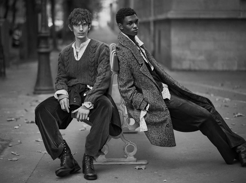 Cirillo and Rouna Obigba sit on a street bench in layered knitwear and a textured overcoat for Zara Studio's fall-winter 2026 campaign